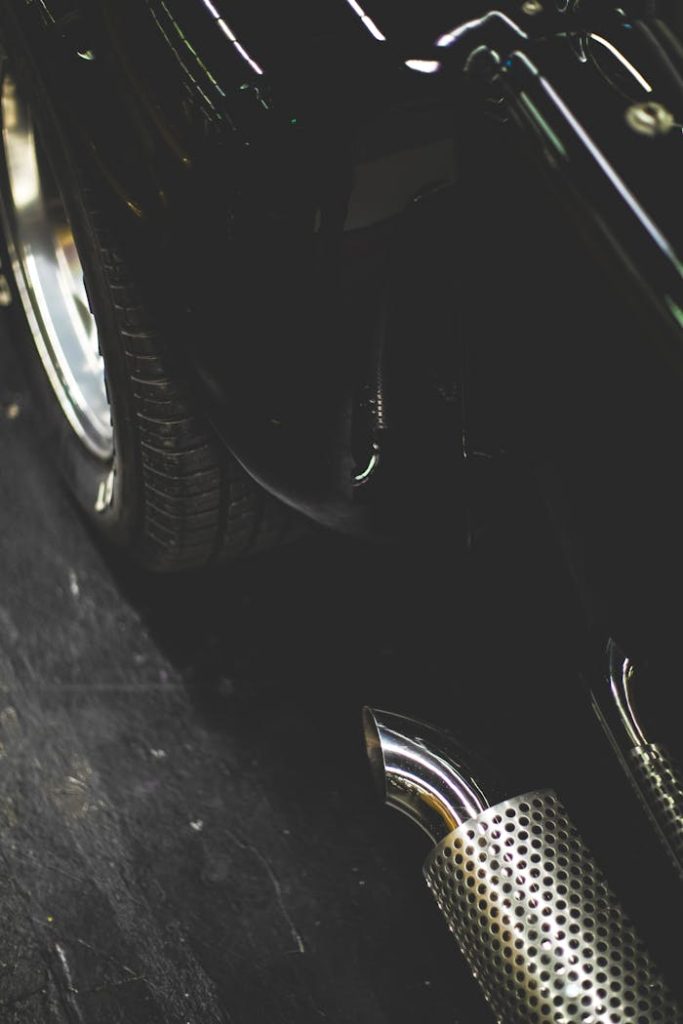 Detailed view of a vintage cars shiny chrome exhaust and tire reflecting ambient light.