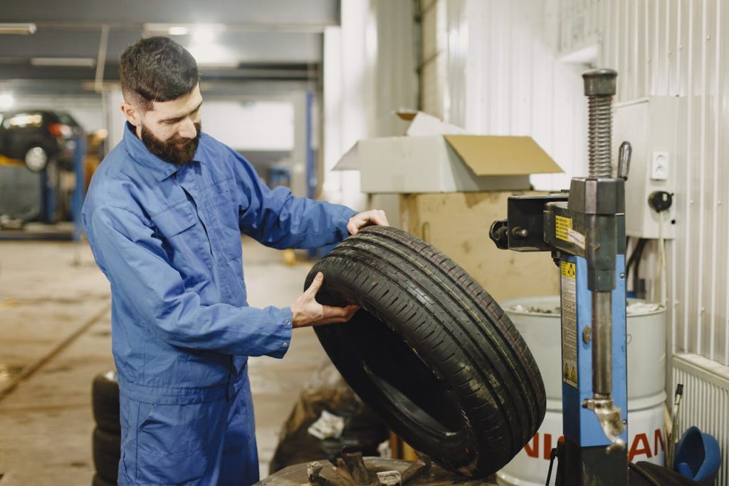 Mastering the First Impression: Your intriguing post title goes here Mechanic in blue uniform examining a tire in an automotive garage.