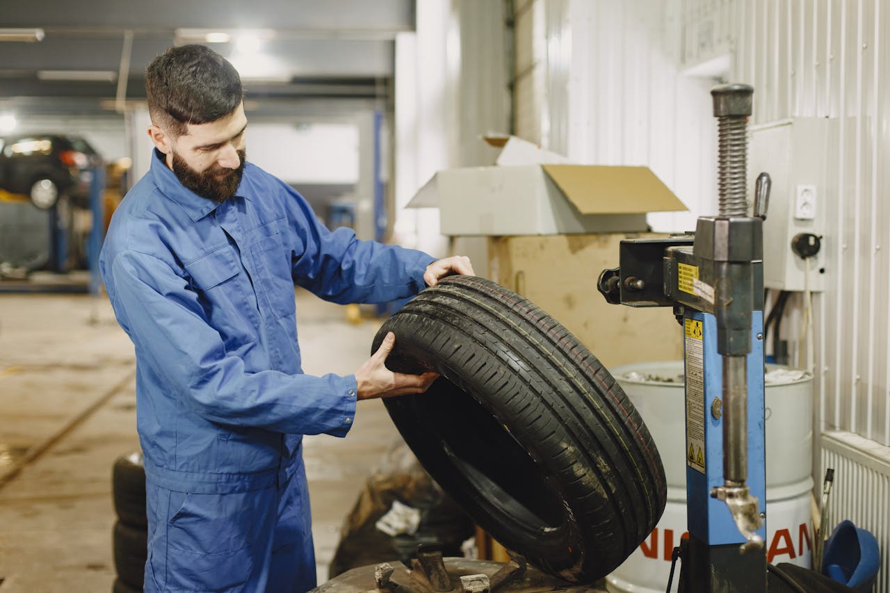 Mastering the First Impression: Your intriguing post title goes here Mechanic in blue uniform examining a tire in an automotive garage.